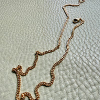 18k Gold curb chain necklace on a textured light blue surface