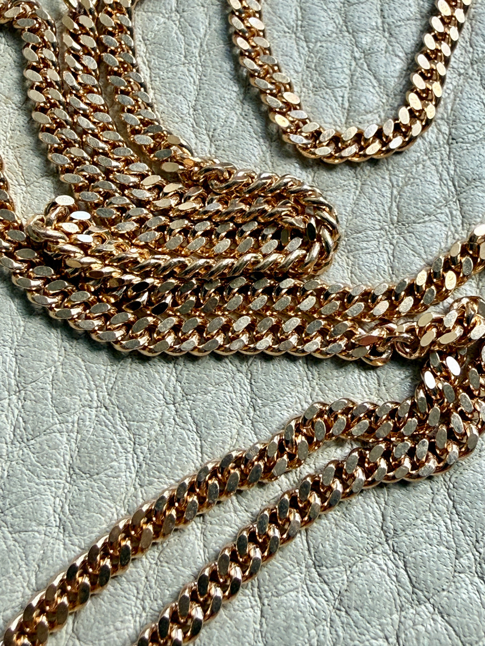 18k Gold curb chain necklace on a textured light surface