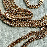 18k Gold curb chain necklace on a textured light surface
