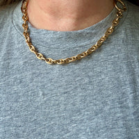 Gold chain necklace on a person wearing a gray shirt
