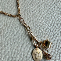 Gold necklace with various charms on a textured light gray background