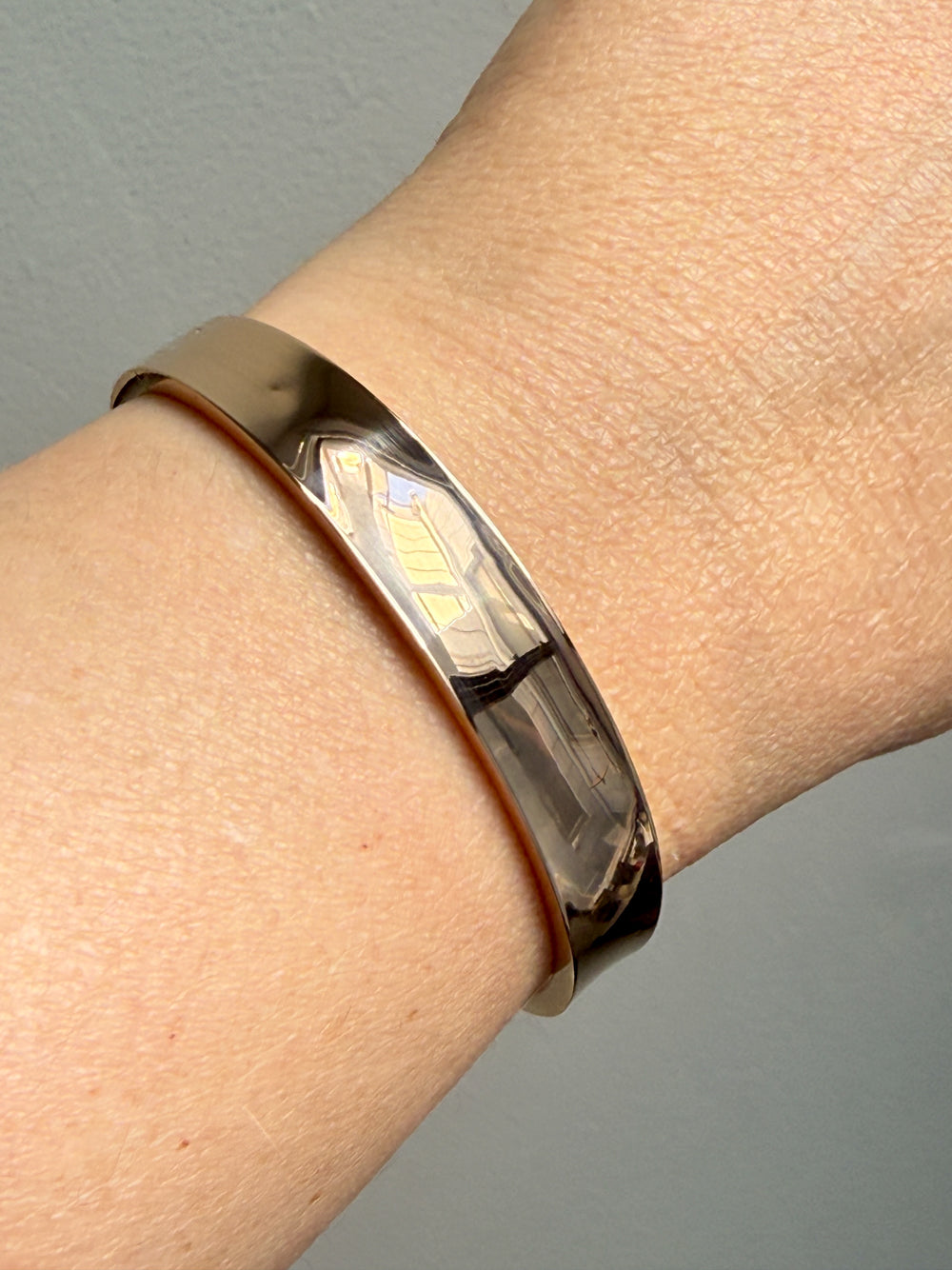 1960s era Vintage Danish 14k Gold Hinged Bangle Bracelet – 7 inch Interior Circumference on wrist over gray background