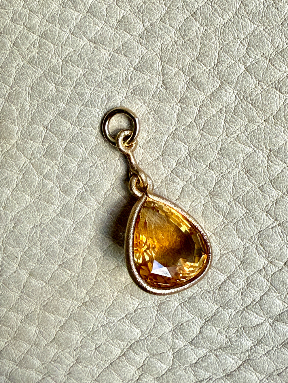 Teardrop-shaped citrine pendant on a light textured background