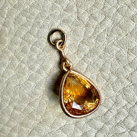 Teardrop-shaped citrine pendant on a light textured background
