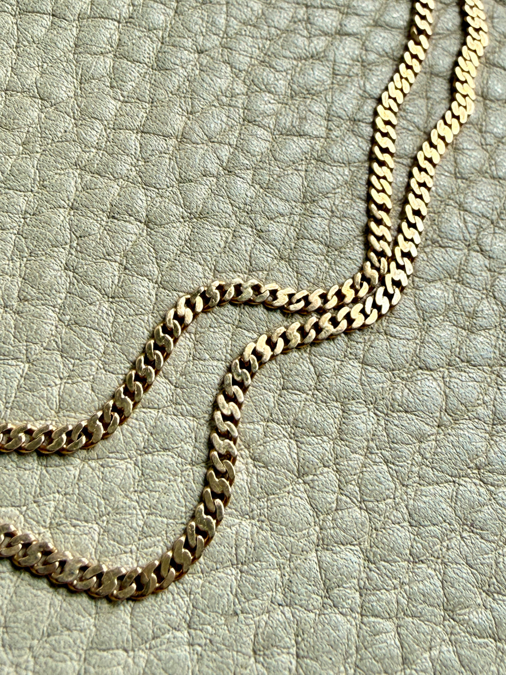 Gold chain necklace on a textured light gray surface