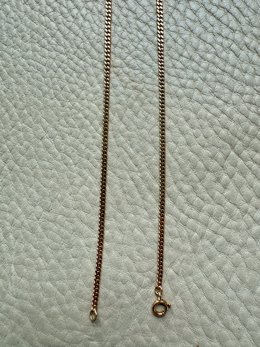 Gold chain necklace on a textured light blue surface