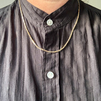 Person wearing a dark shirt with a gold chain necklace 