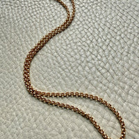 18k gold vintage rolo chain necklace on a textured light gray surface