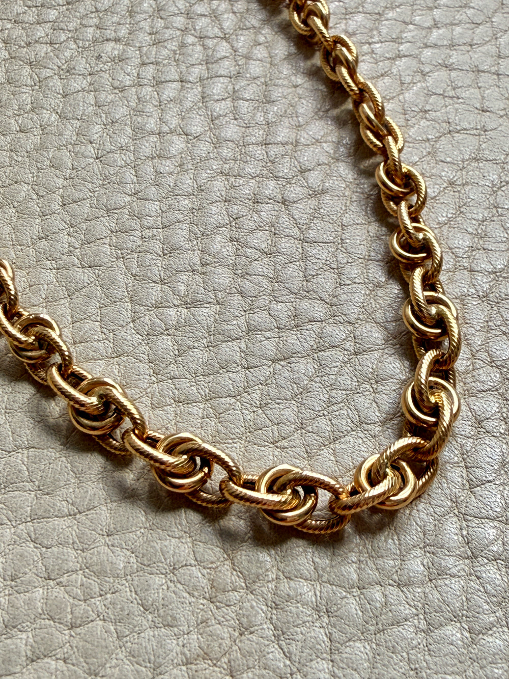 Gold chain necklace on a textured light gray background