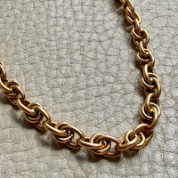 Gold chain necklace on a textured light gray background
