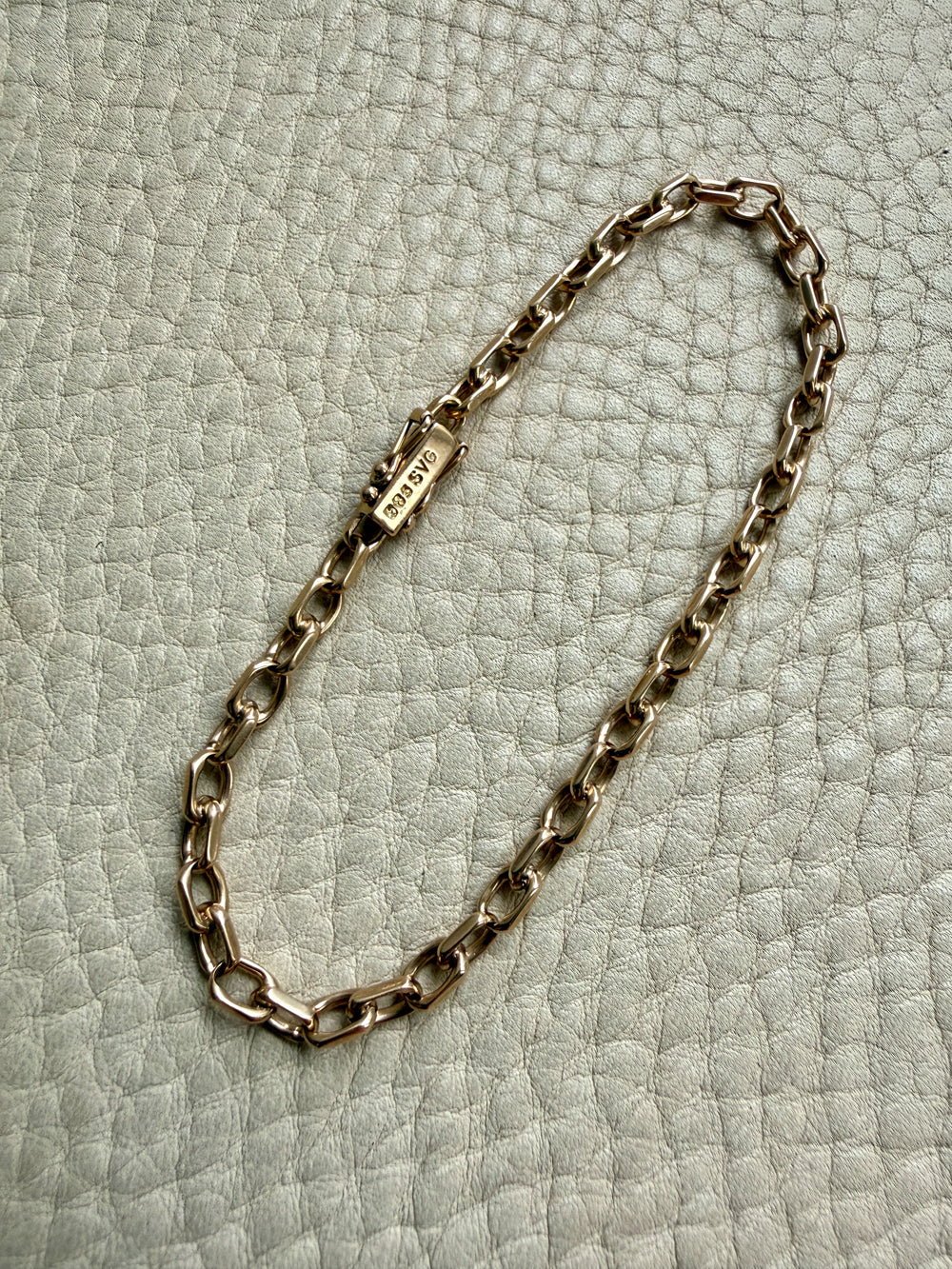 14k Gold vintage biker chain bracelet on a textured light gray background