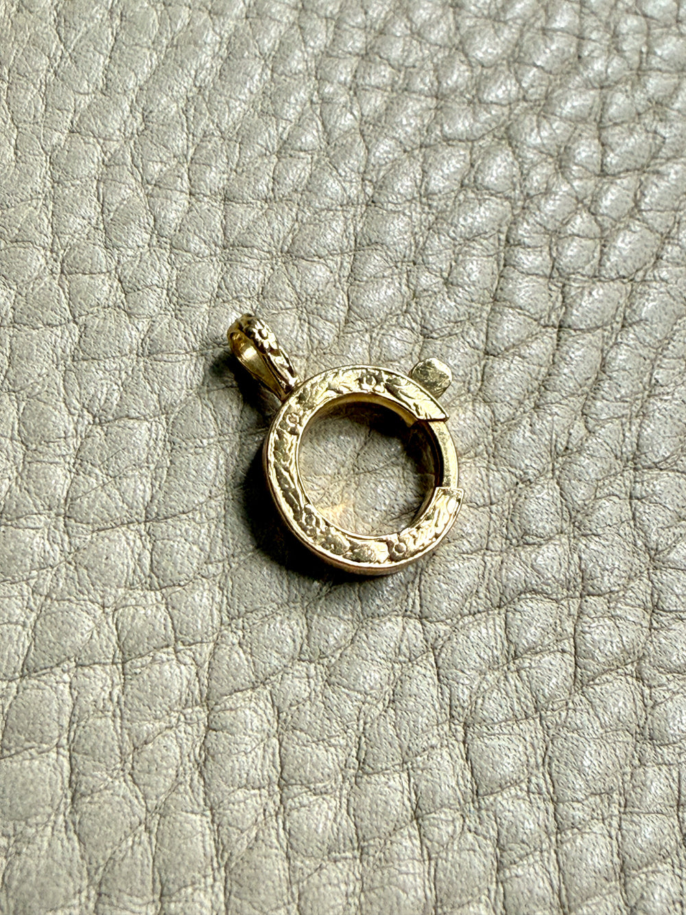 Gold bolt clasp pendant on a textured gray surface