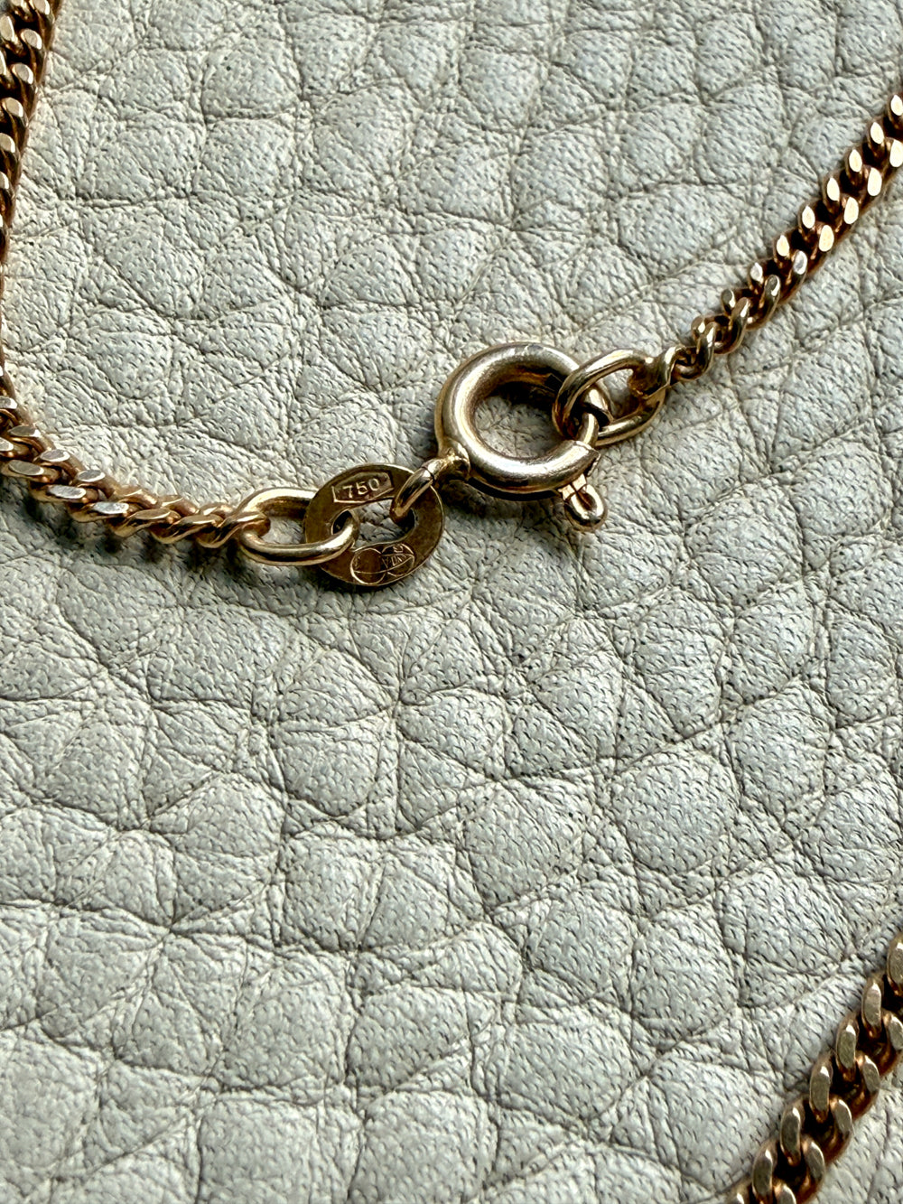 Gold chain necklace on a textured light gray surface