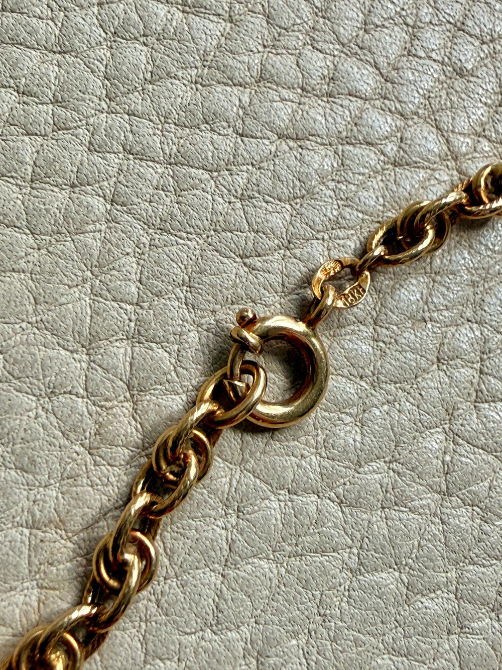 Gold chain necklace on a textured light gray background