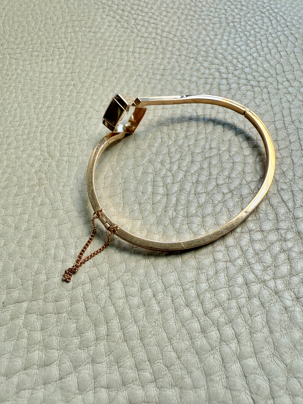 Gold bracelet on a textured light gray surface