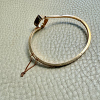 Gold bracelet on a textured light gray surface