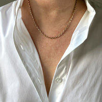 Person wearing a gold chain necklace with a white shirt