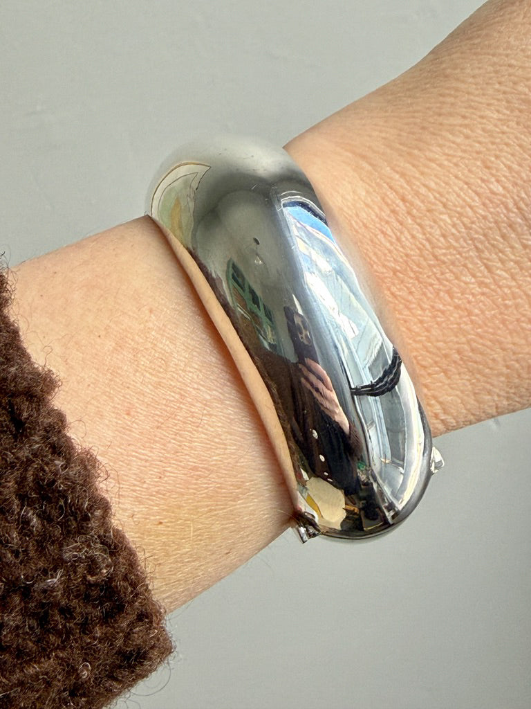Silver donut bracelet on a wrist with a neutral background