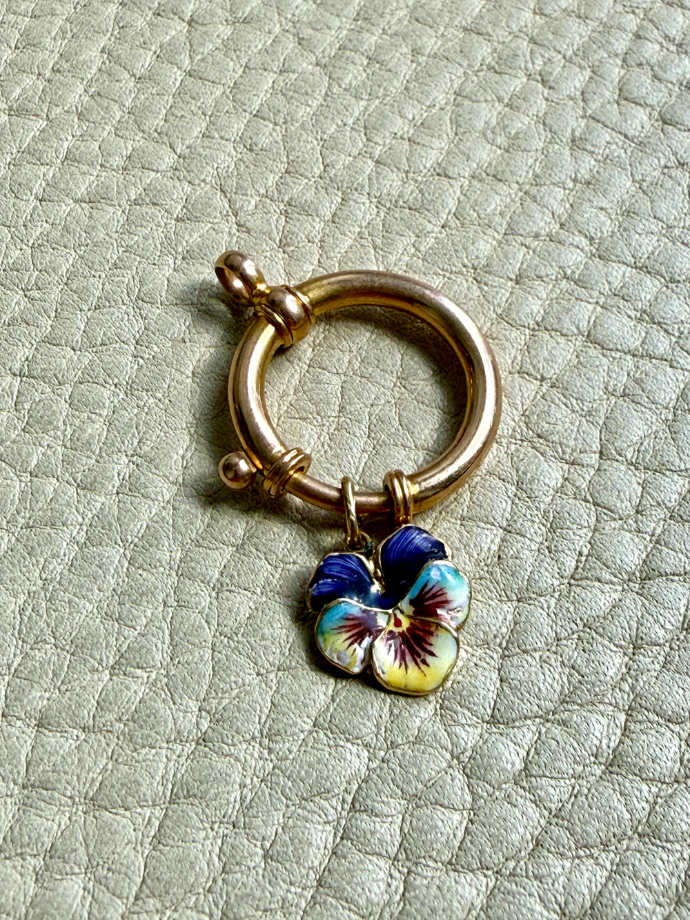 antique 18k gold large bolt clasp with a blue and yellow flower charm on a textured light gray background penelopepenelope.com