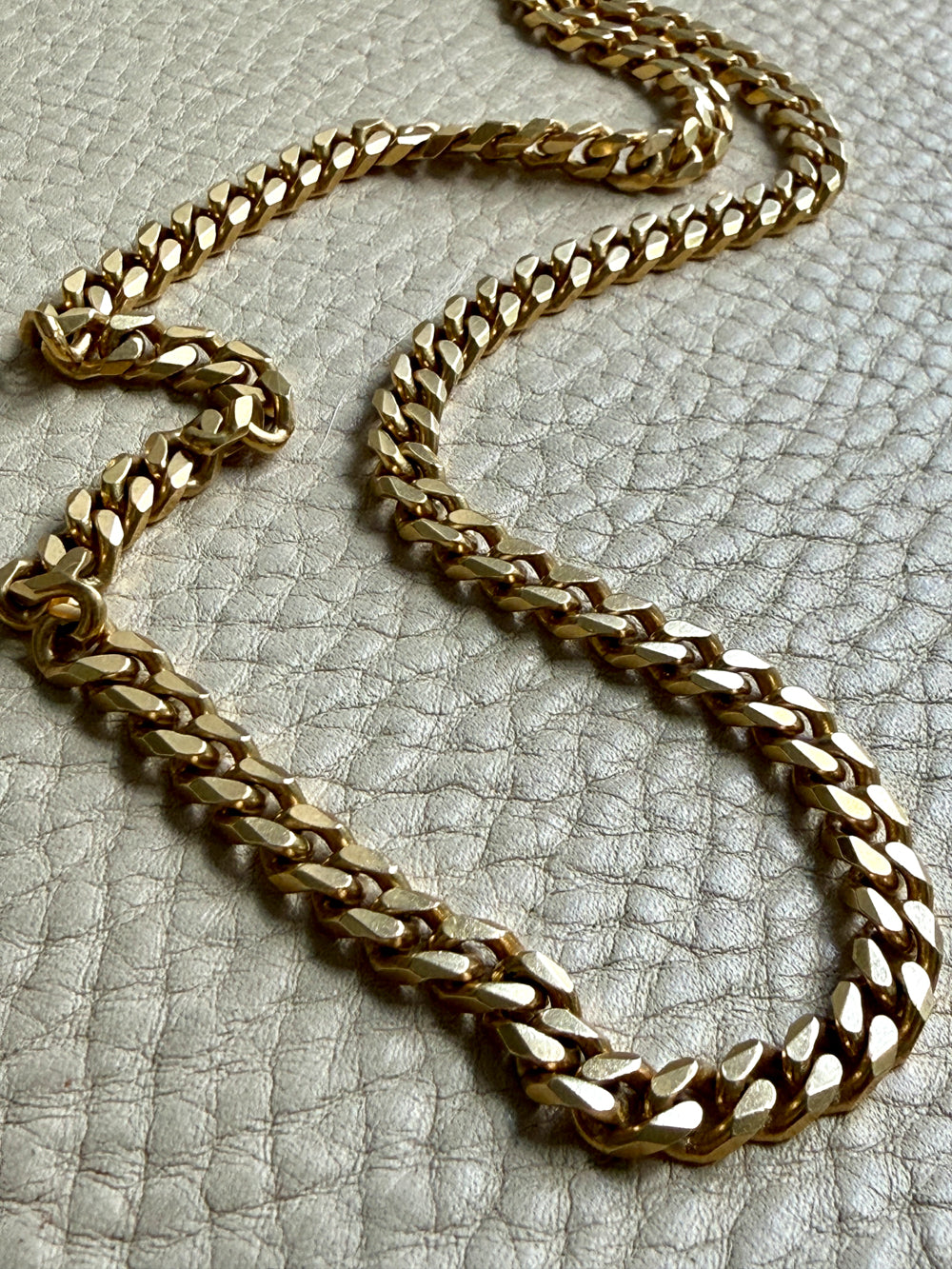 Gold chain necklace on a textured gray surface