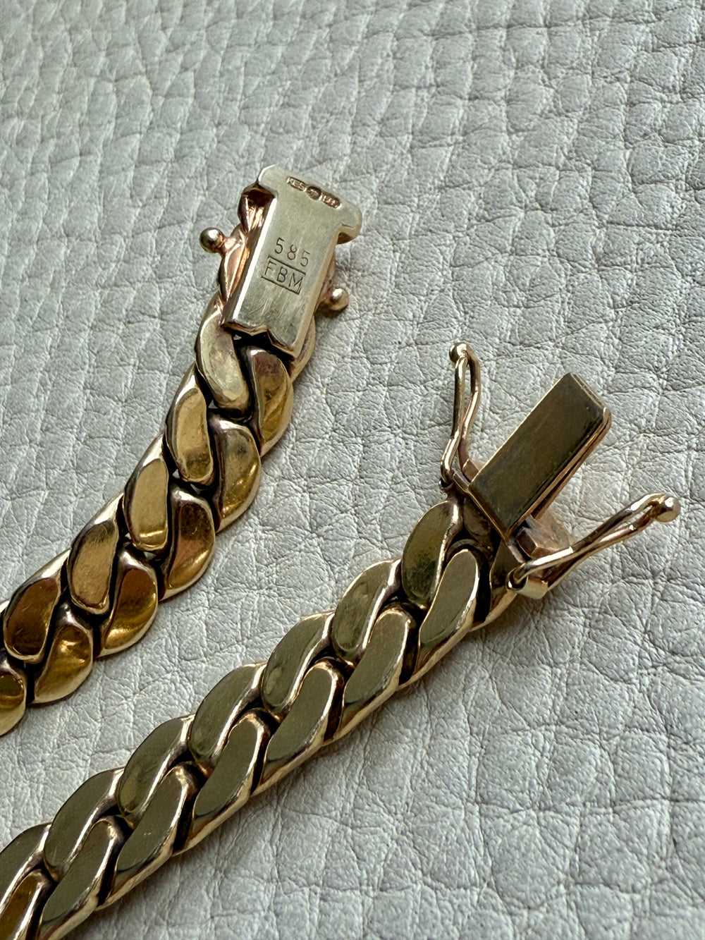 Gold chain bracelet on a textured light gray surface