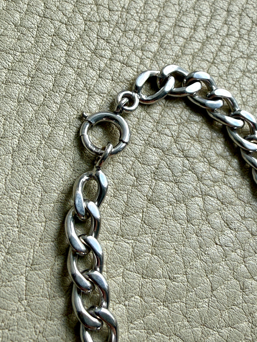 Close-up of a vintage 14k white gold chain on a textured beige surface