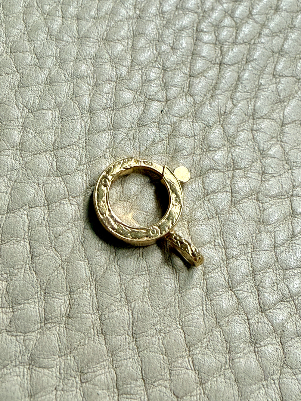 Gold bolt clasp pendant on a textured gray surface