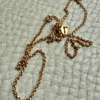 18k Gold rolo link necklace on a textured light green surface