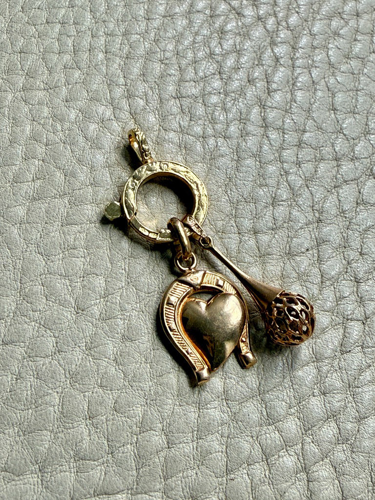 Gold charm with heart, horseshoe on a textured gray background
