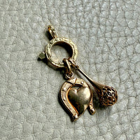 Gold charm with heart, horseshoe on a textured gray background