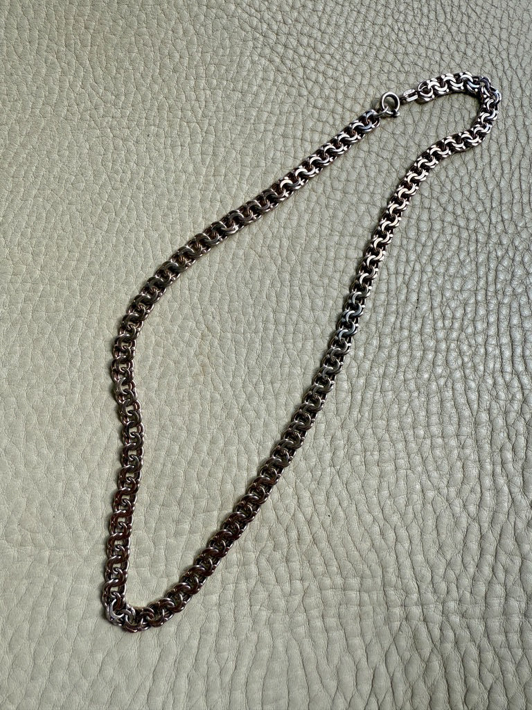 Silver chain necklace on a textured beige surface
