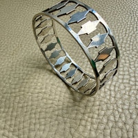 Silver bracelet with arrow design on a textured beige surface