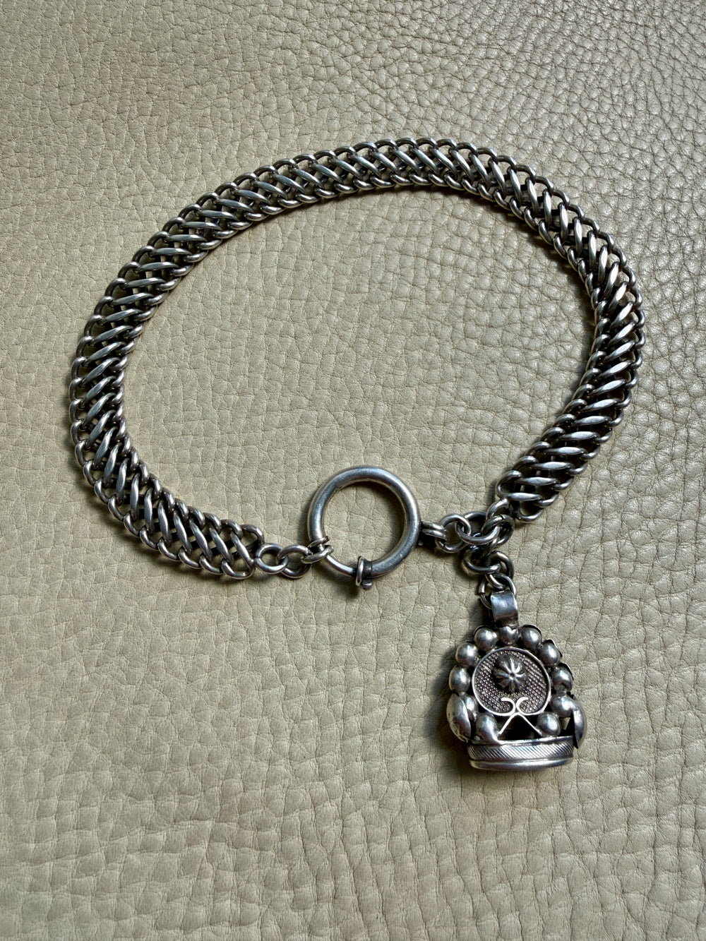antique Silver watch chain with large bolt clasp on a textured beige surface