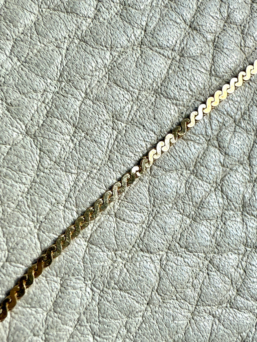 Gold chain on a textured light gray surface