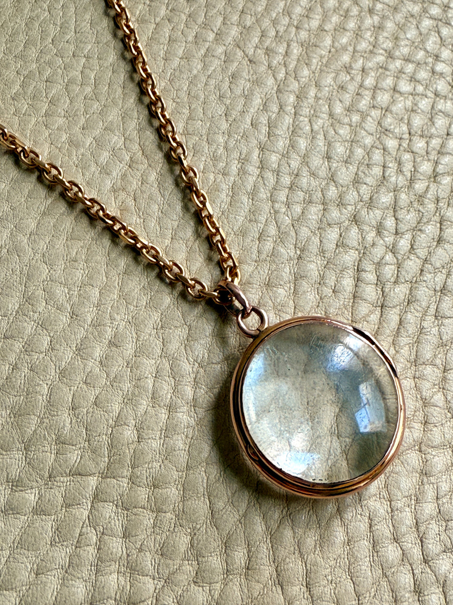 glass and gold Necklace with a round pendant on a textured beige background
