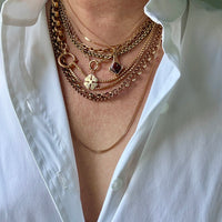 Person wearing multiple gold necklaces on a white shirt background