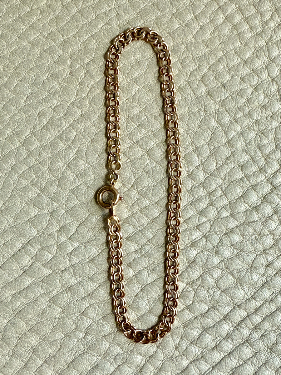 Gold chain bracelet on a textured light green background