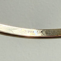Gold bracelet with 'PRH 585' engraving on a gray background