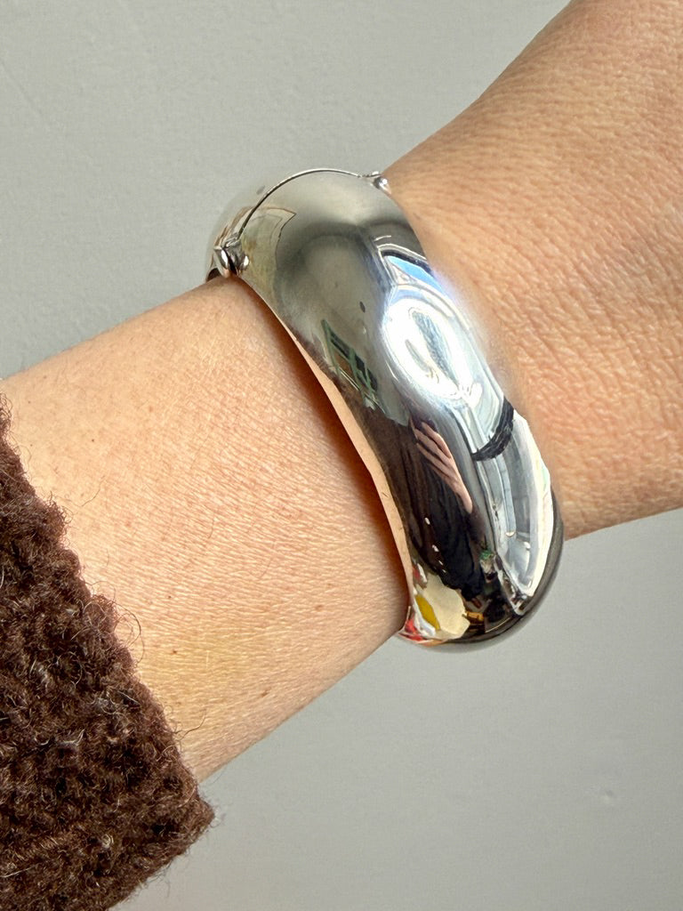 Silver bangle on a wrist against a neutral background