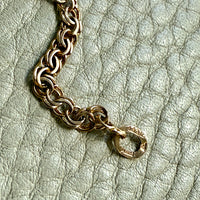 Gold chain bracelet on a textured light green surface
