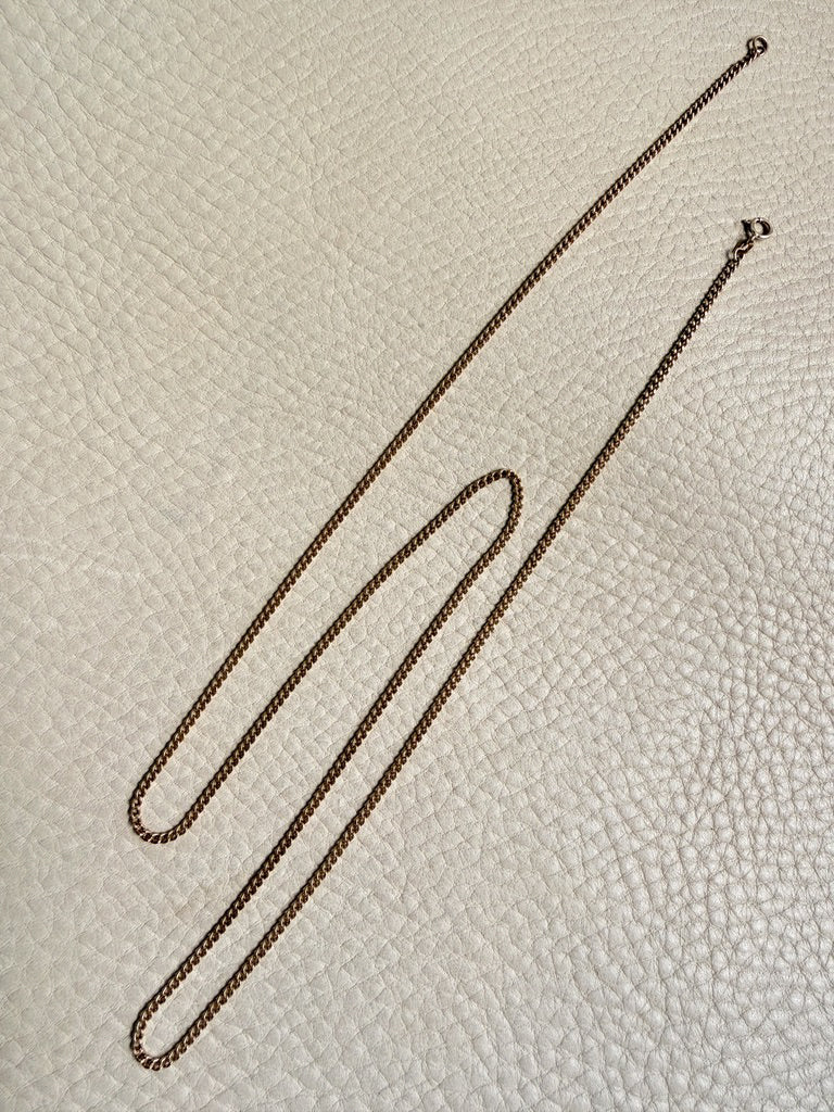 Gold chain on a textured beige surface