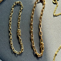 Gold chain bracelets on a gray surface