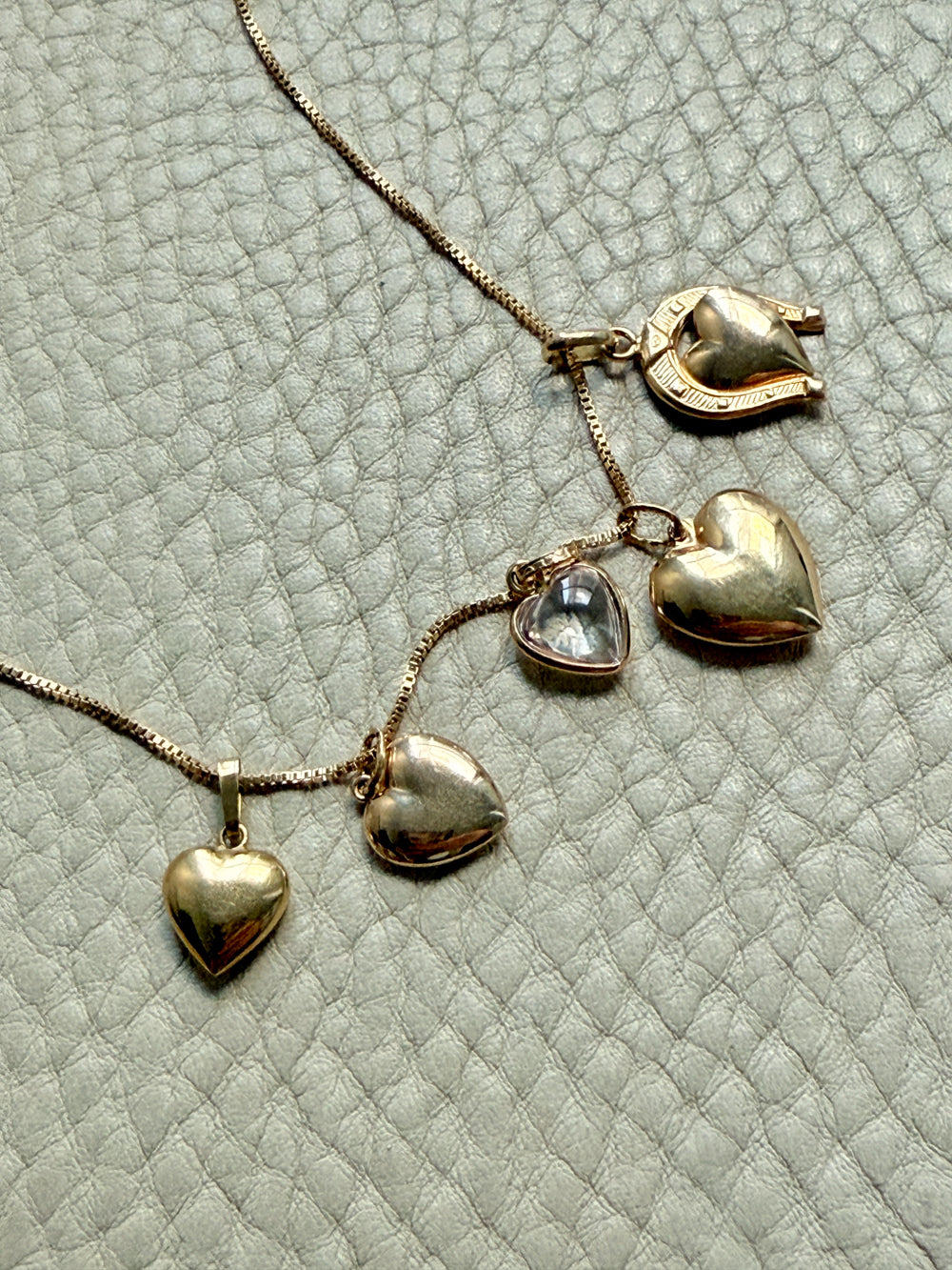 Gold heart-shaped necklace on a textured light gray background