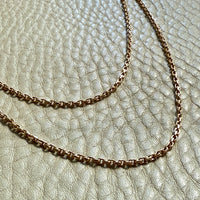18k gold chains on a textured beige surface