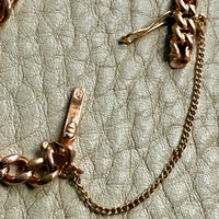 Gold chain bracelet on a textured beige surface