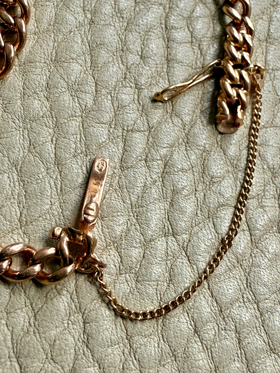 Gold chain bracelet on a textured beige surface