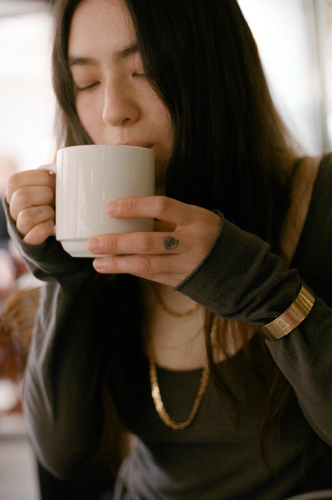 Woman drinking from a white mug with a blurred background