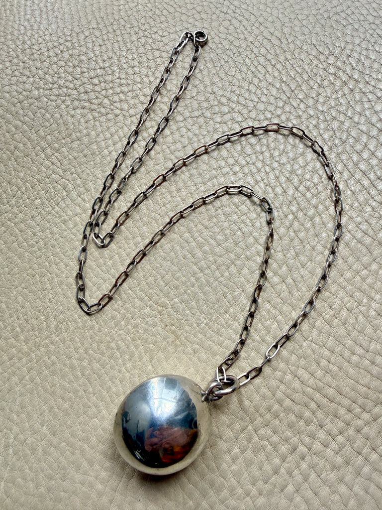 Silver necklace with a round pendant on a textured beige surface