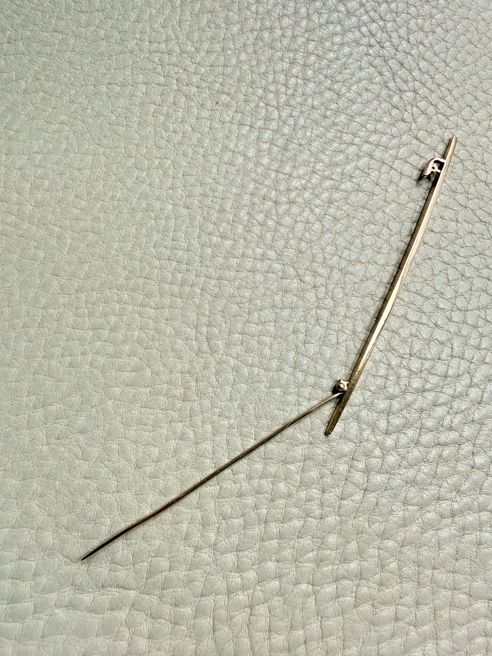 18k gold antique brooch on a textured beige background