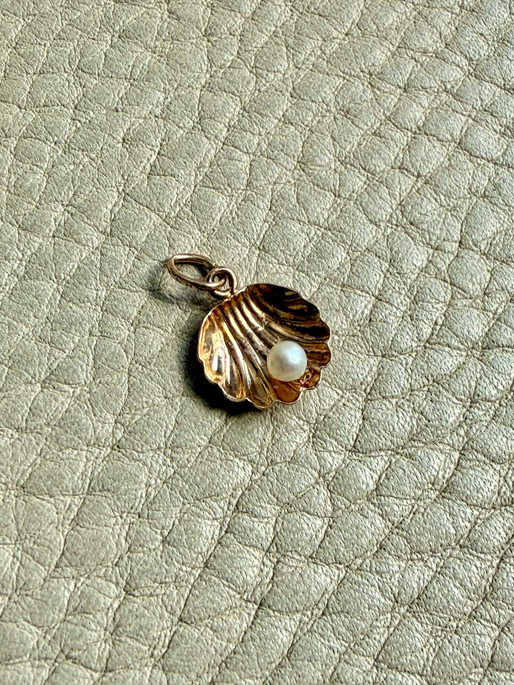 vintage 14k Gold shell charm with a pearl on a textured beige background